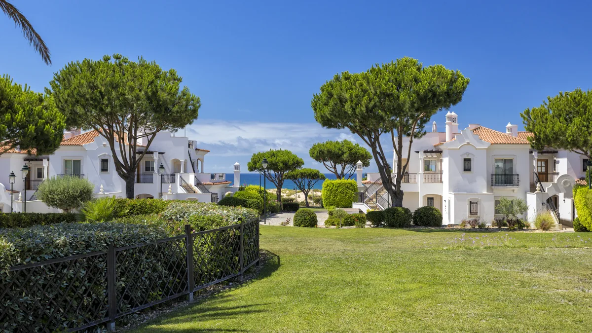 Townhouses among stone pines, with the sea beyond, at Dunas Douradas Beach Club