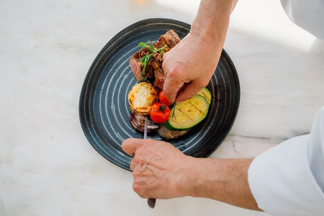 Chefe a empratar ribeye com legumes grelhados