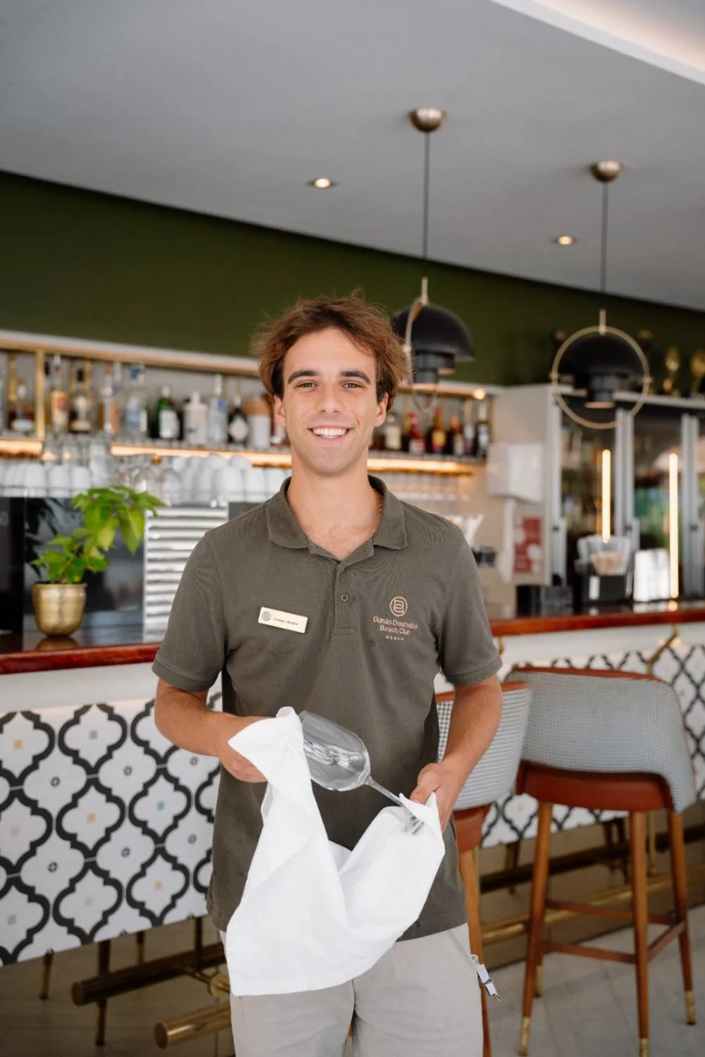 Colaborador do Saudade a polir um copo ao balcão do bar