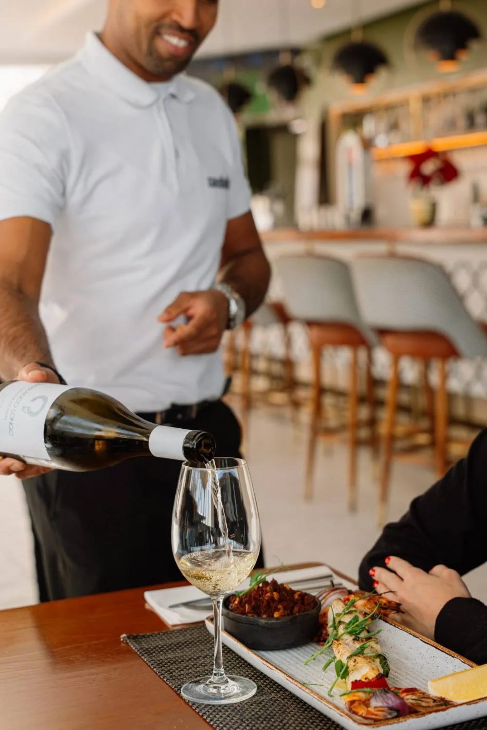 Dietmar a servir vinho branco à mesa no Saudade